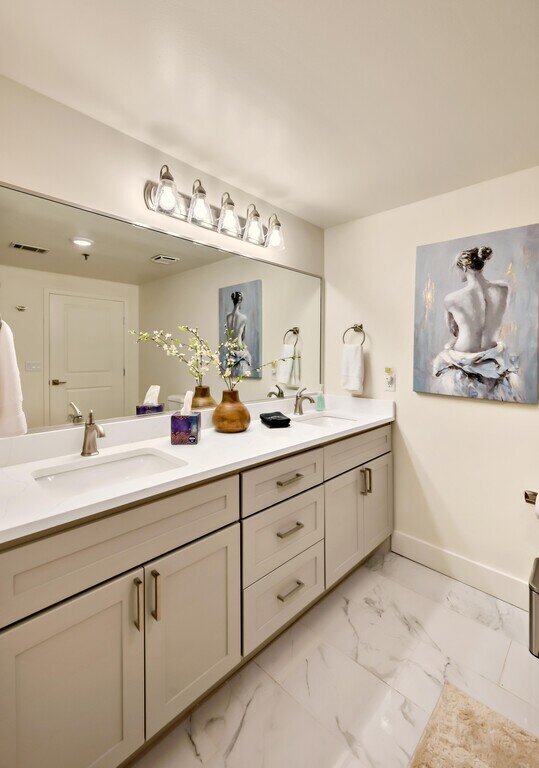 Beautifully decorated bathroom with large mirror in this 2 bedroom, 2.5 bathroom luxury vacation rental loft condo for 8 guests with incredible downtown views, free parking, free wifi and professional decor in downtown Waco, TX.