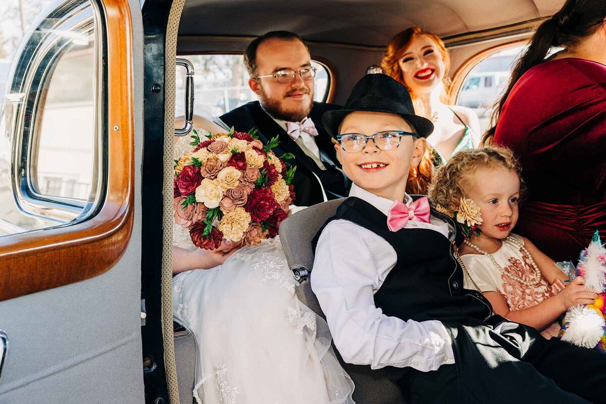 Bridal party sitting in 1940's limousine on wedding day