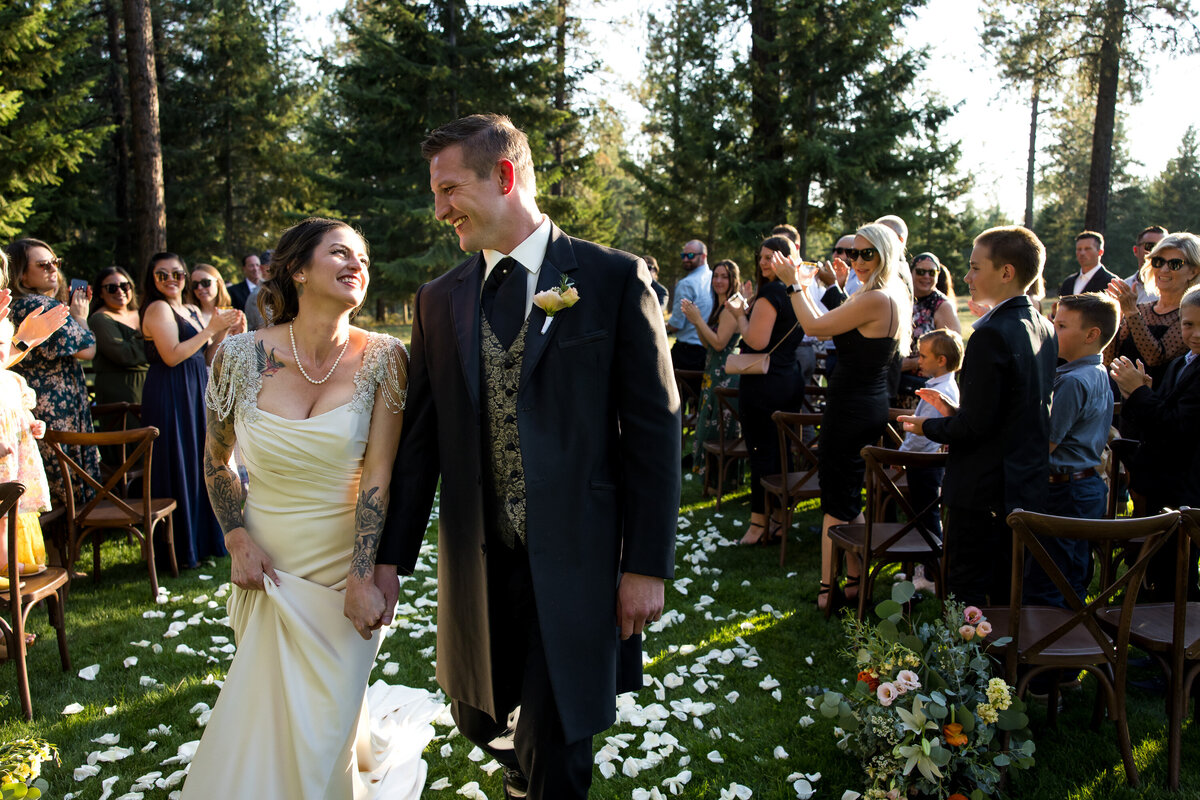 Newlyweds exit their Cider Mountain wedding ceremony all smiles after being showered with flower petals near Athol, Idaho.