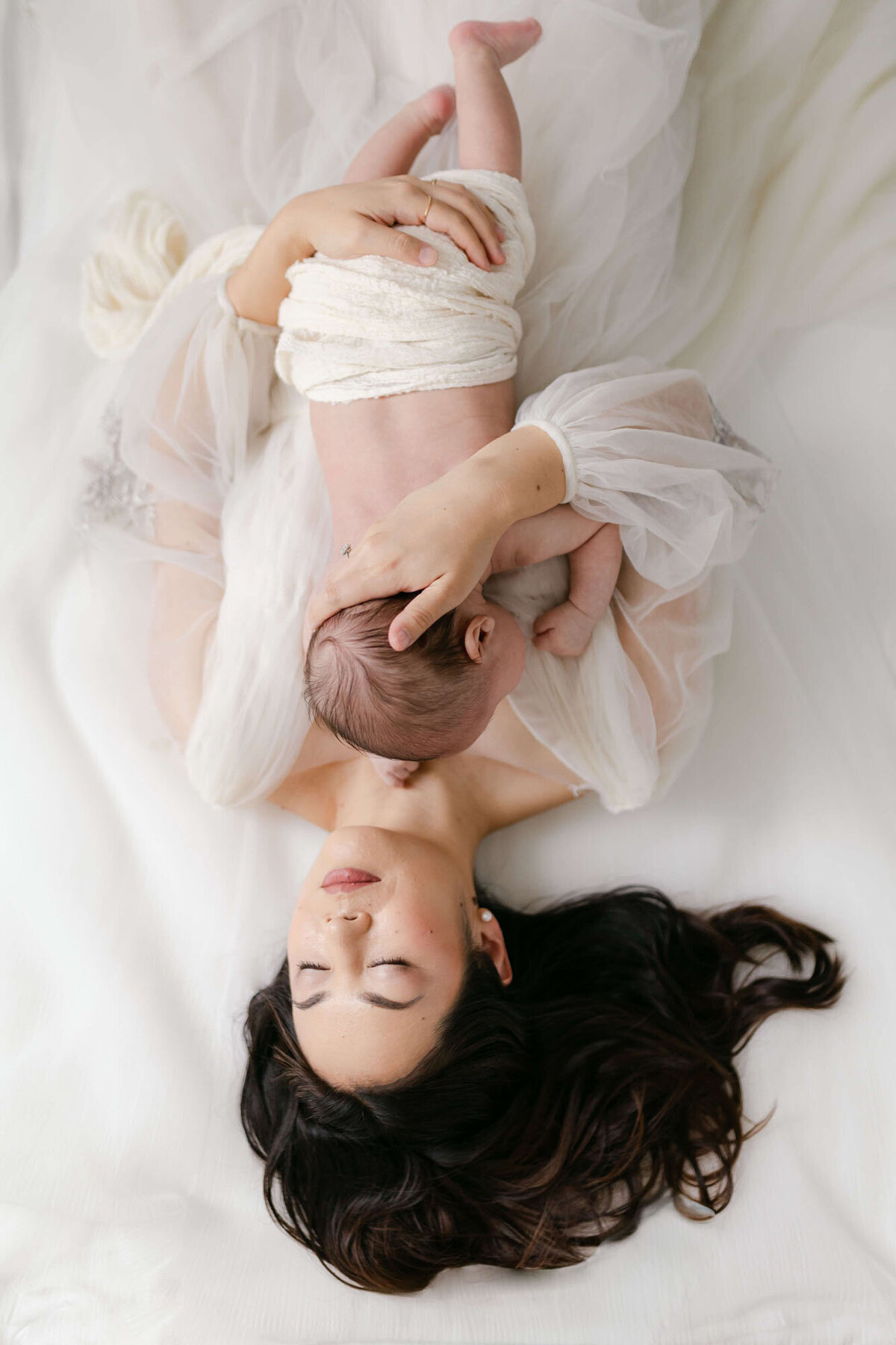 Mother on bed with newborn during intimate Bay Area newborn photography session.