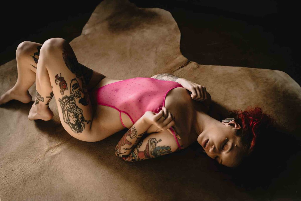 Heavily-tattooed-women-laying-on-cow-hide-hot-pink-lingerie