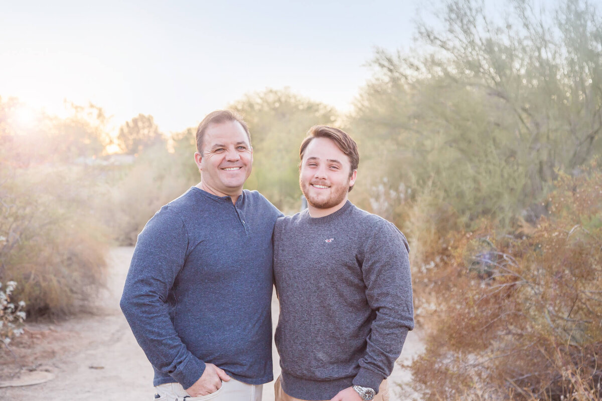 brown haired father and son in blue and gray shirts standing on a desert park path in Gilbert, AZ