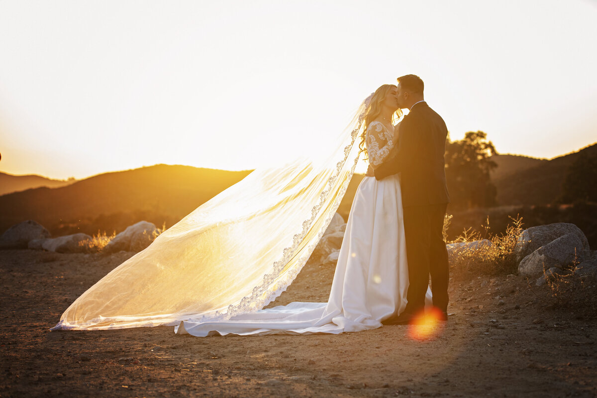 Newlyweds in glowing light kissing  in California mountains