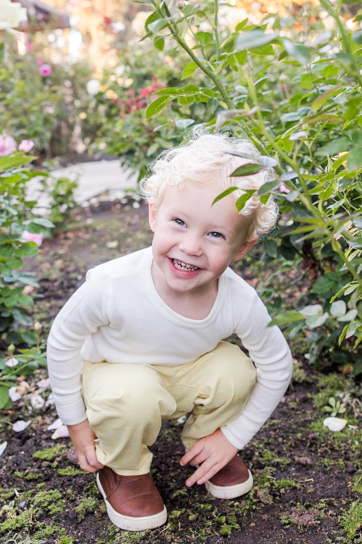 young boy squatting in rose garden san diego
