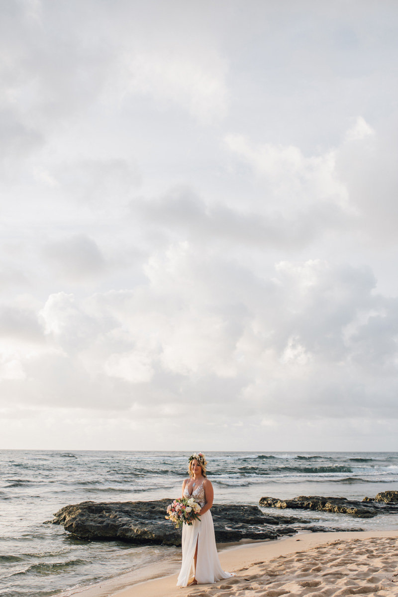 bride walking under a cloudy sky along the edge of the water