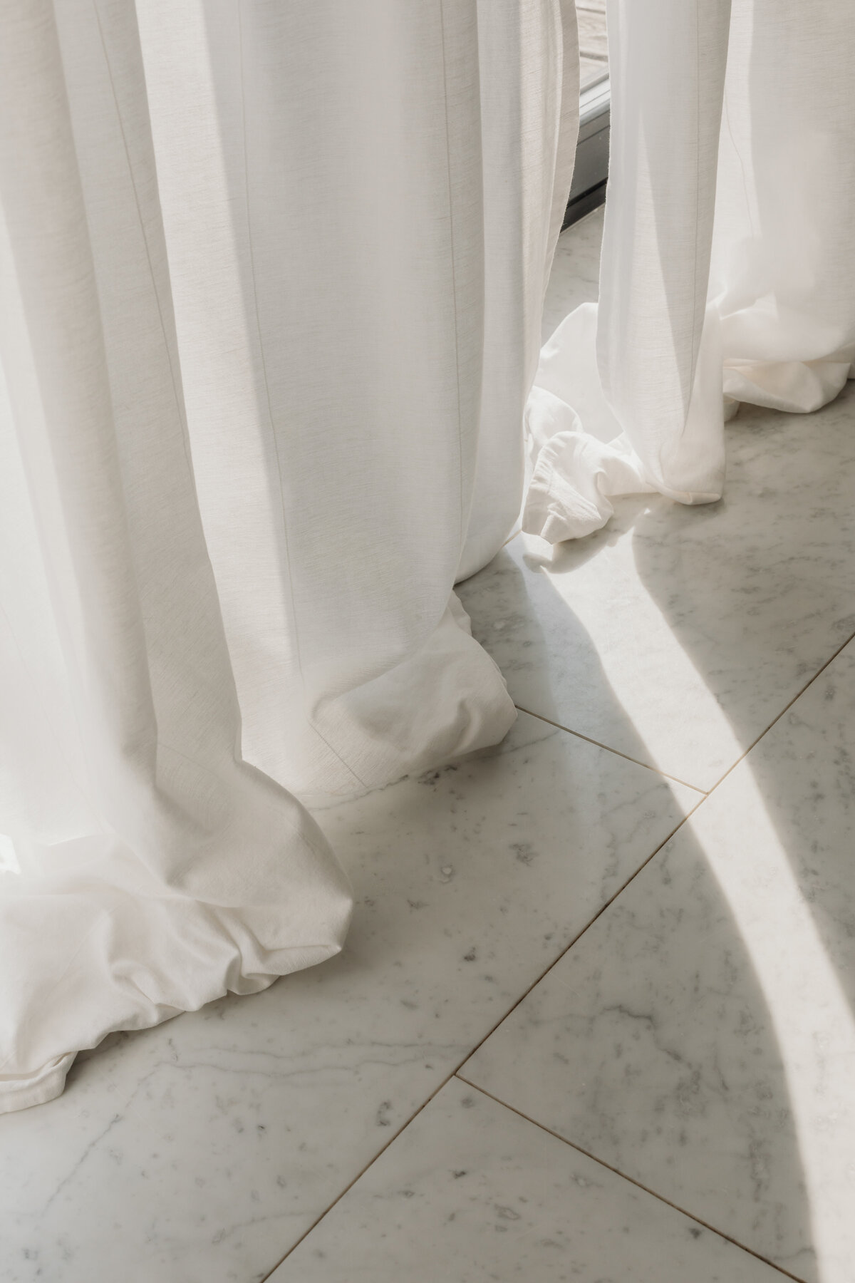 kaboompics_a-close-up-view-of-marble-tile-flooring-with-white-linen-curtains-gently-brushing-the-floor-in-soft-natural-light-36973
