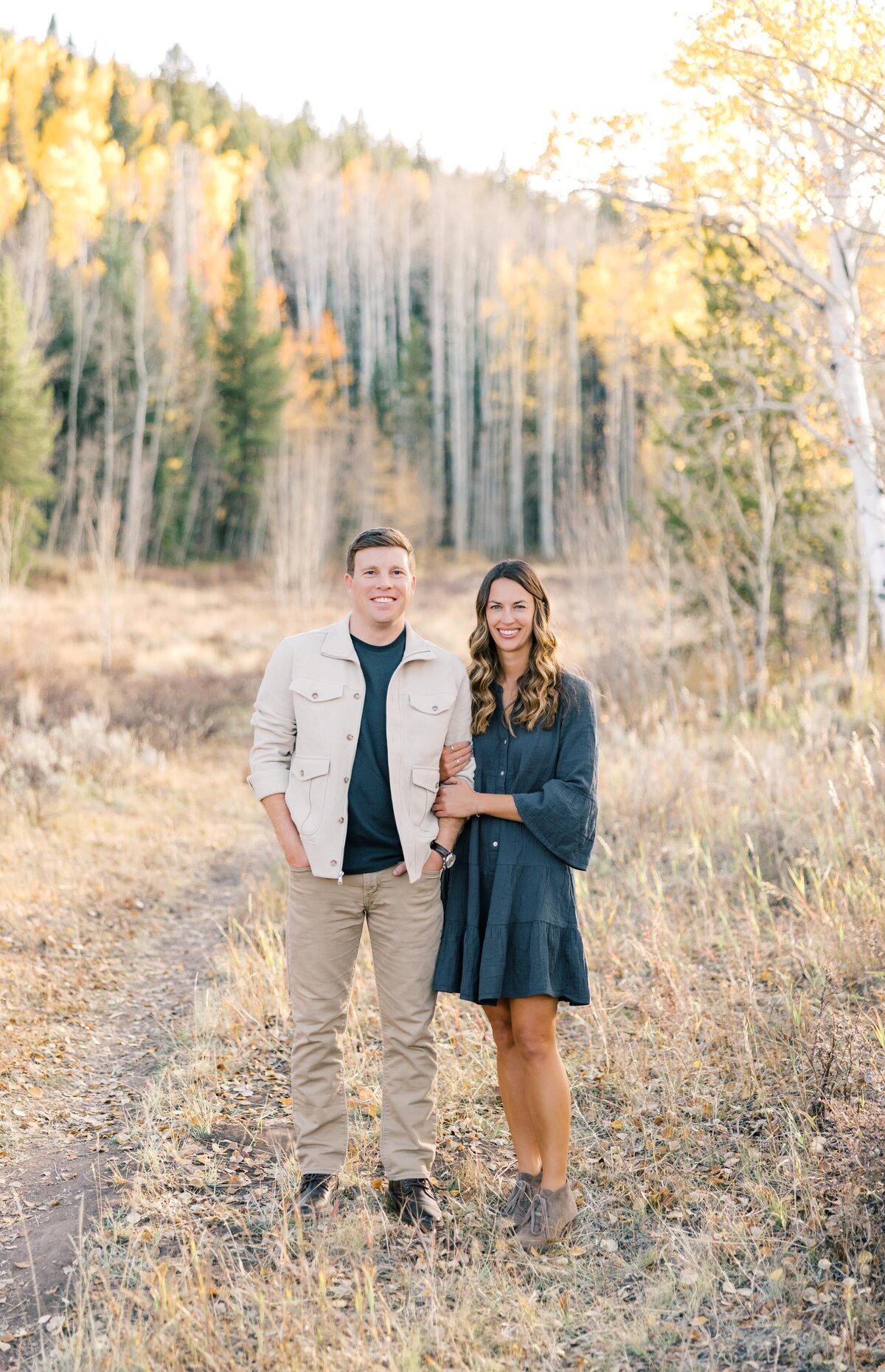 There is a young couple arm in arm. The man is a white button up and the woman is in a blue dress. Taken by a local Breckenridge photographer.