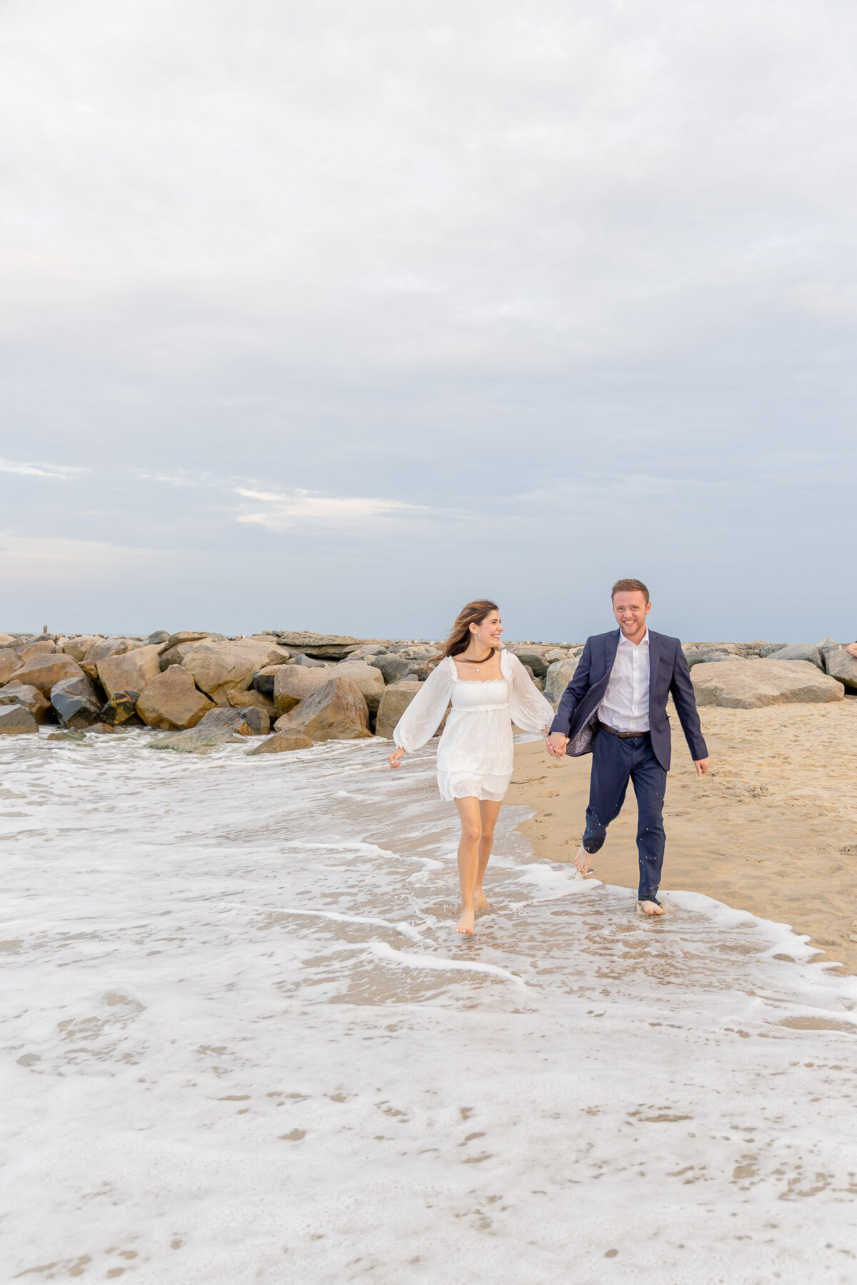 A couple runs down the beach near Raleigh NC towards the camera are just getting engaged.
