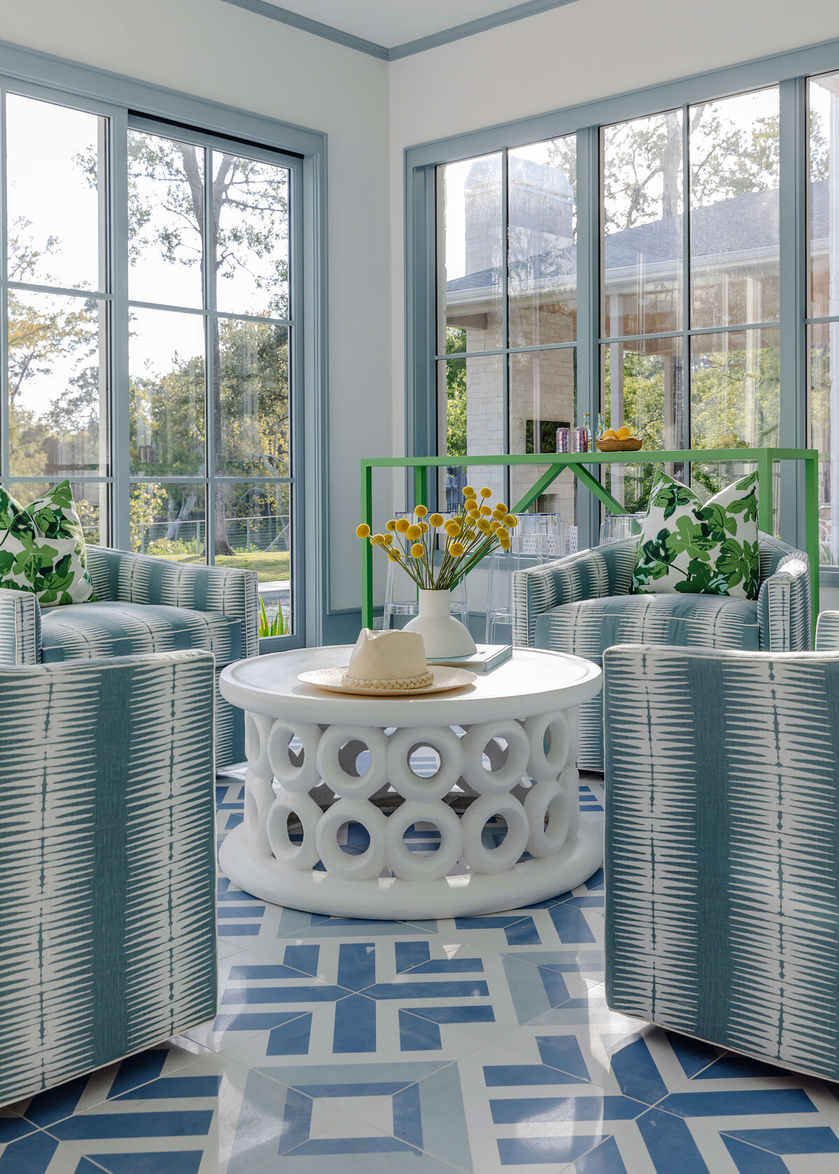 oyster creek studios memorial new build white geometric rug with ceramic coffee table and blue chairs in sunroom