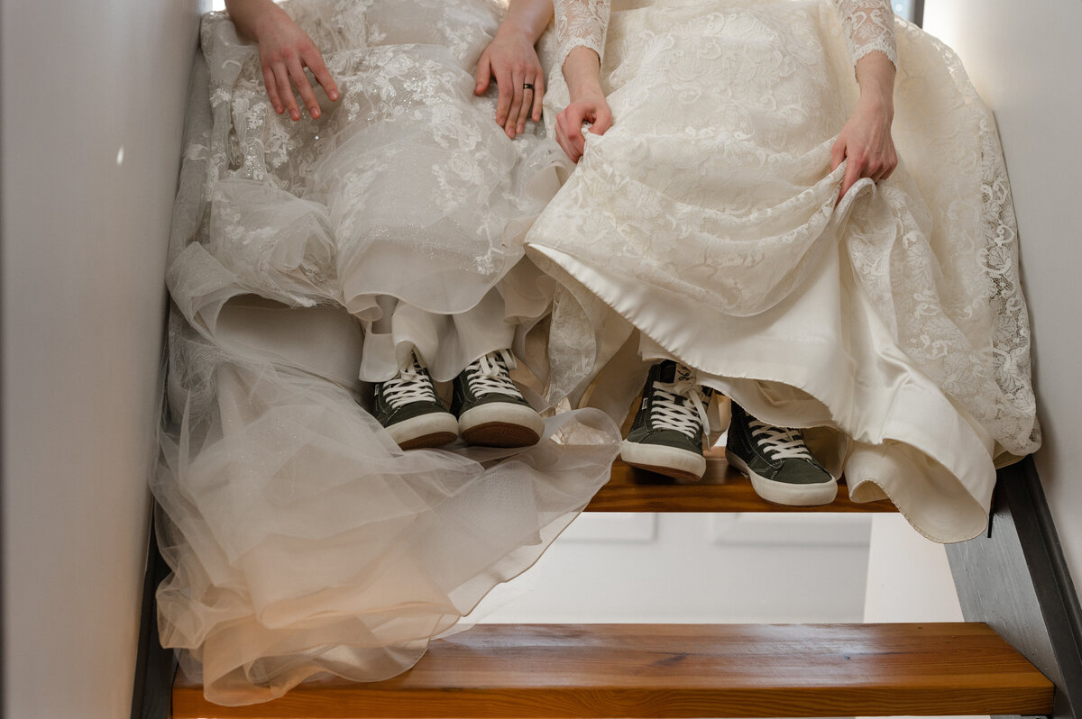 two brides lift up their dresses to reveal matching sneakers