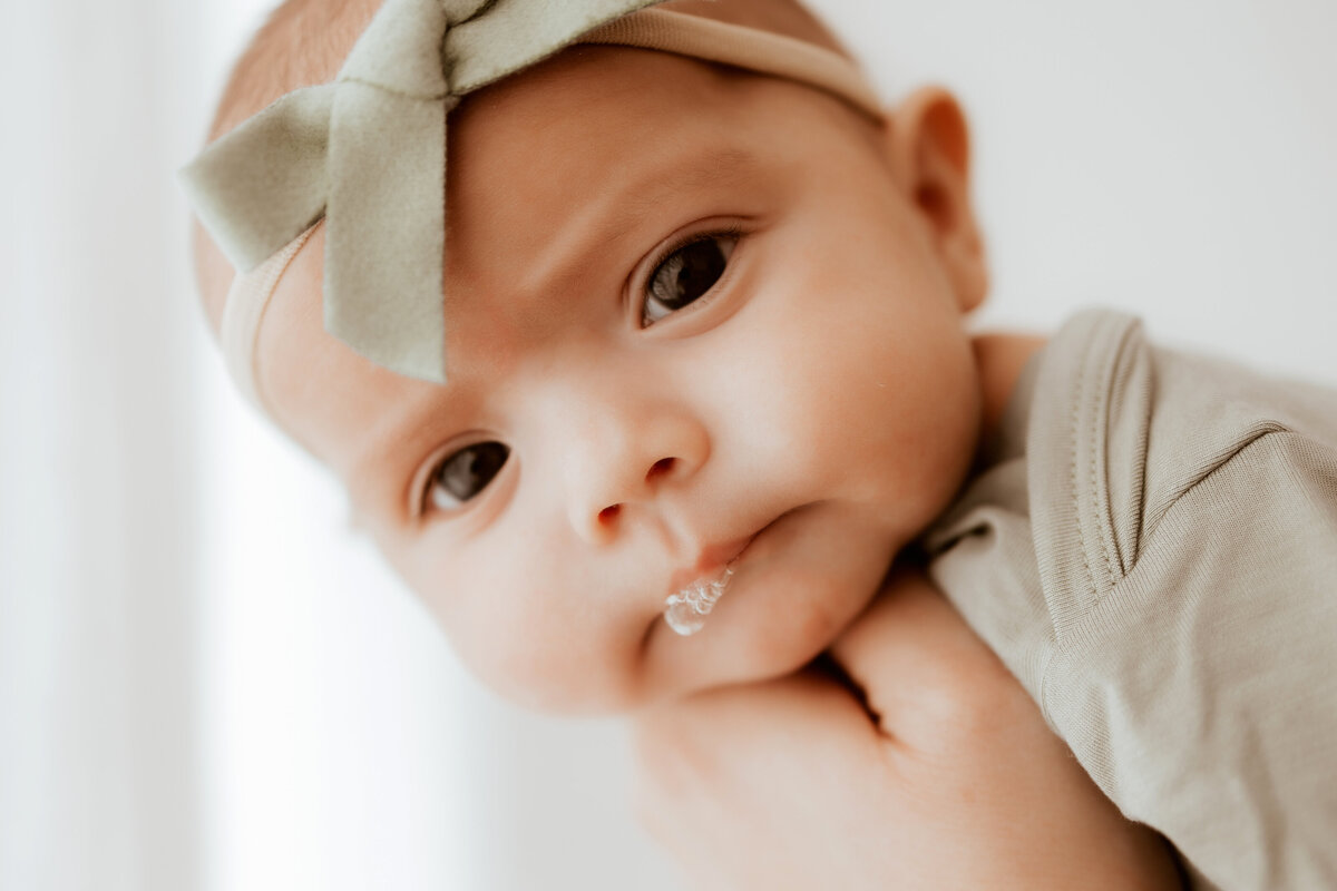 newborn baby girl blowing bublles with bow