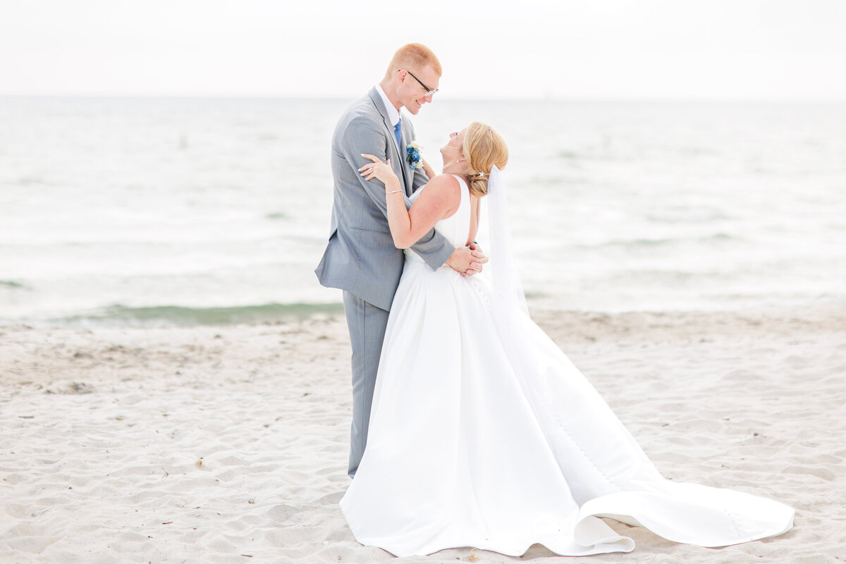 A bride and groom hugging on the beach representing the best Cape Cod wedding photographer