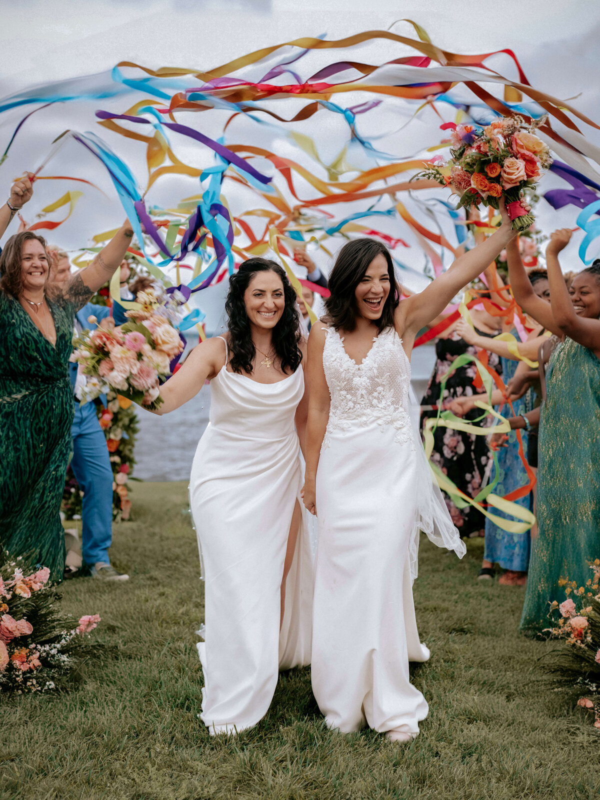 two-brides-walking-through-colorful-ribbons-and-cheering