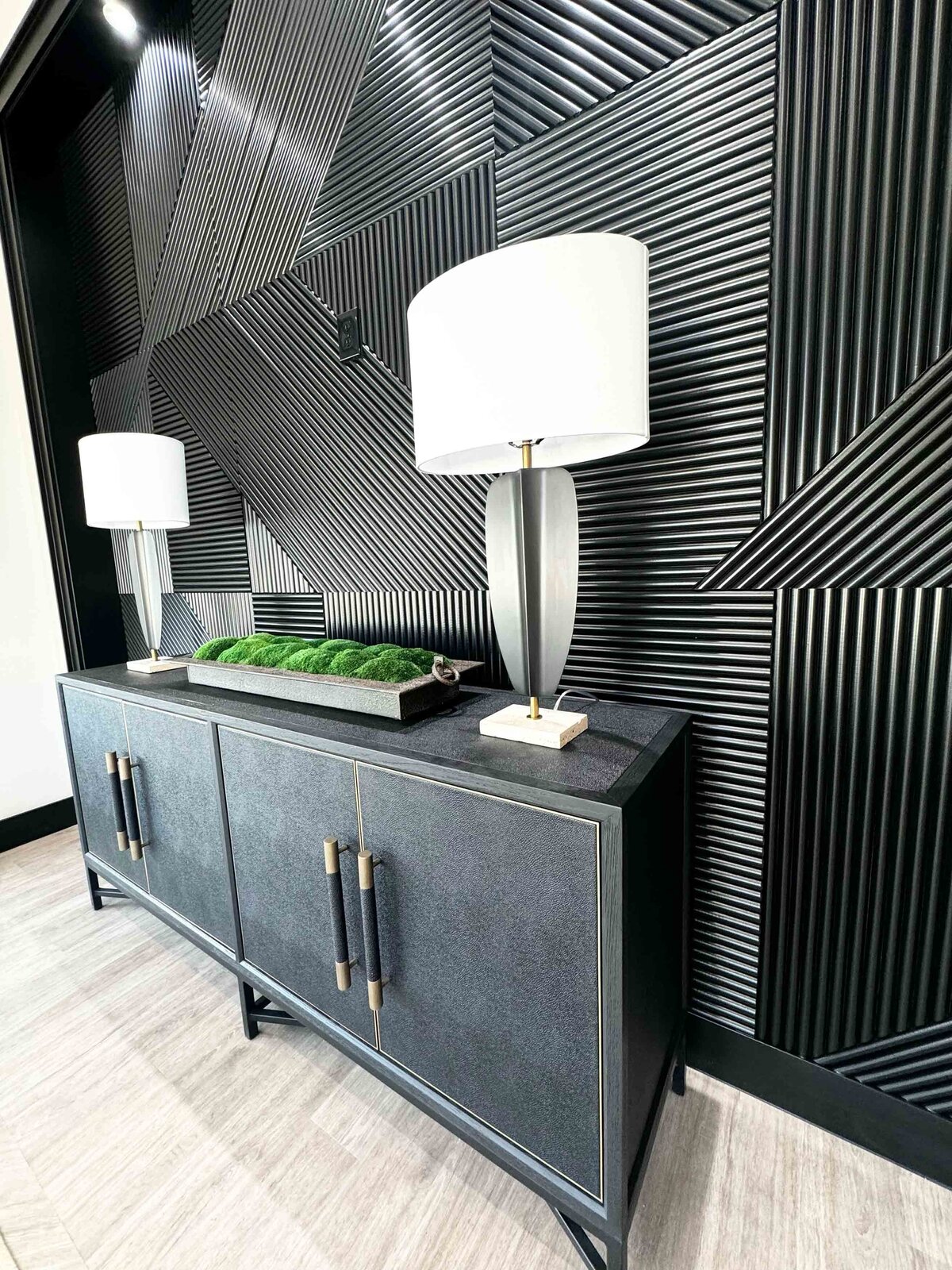Refined home design and décor featuring a black table accessorized with black lamps, complemented by a textured wall design, creating a unique and sophisticated space.