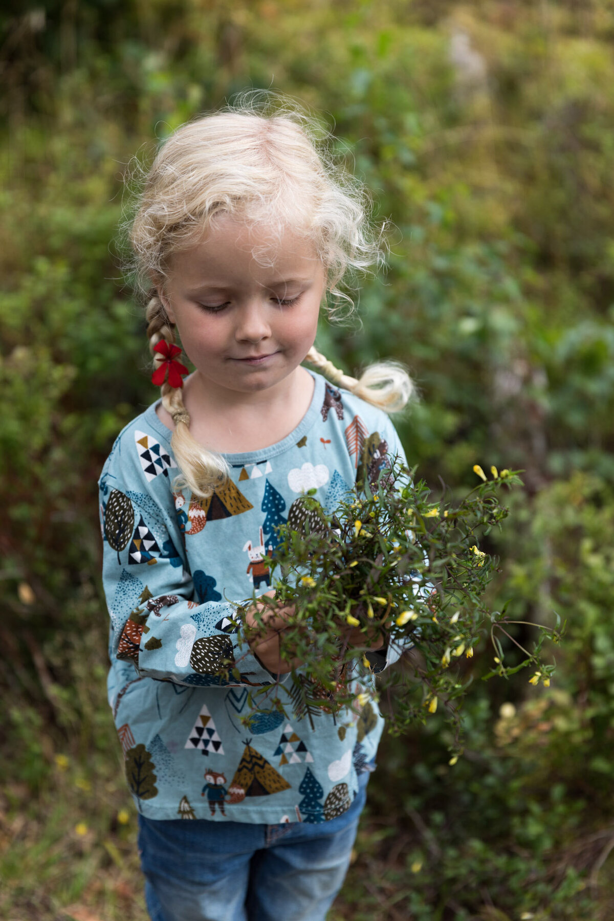Livsstilsfoto av en jente som holder en bukett av lyng og blomster og ser på buketten.