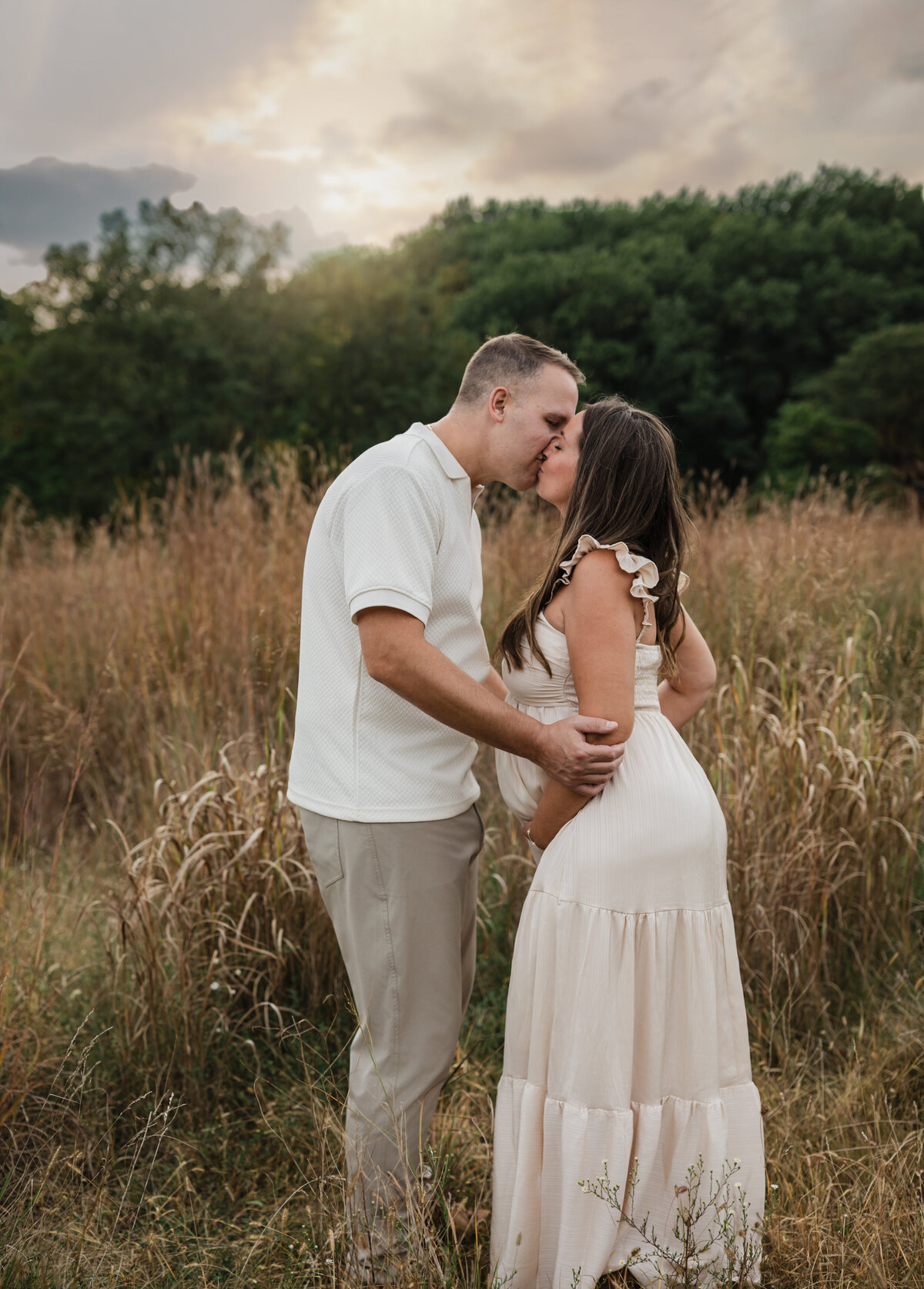 husband and pregnant wife in pink silk maternity gown holding baby bump for maternity photoshoot