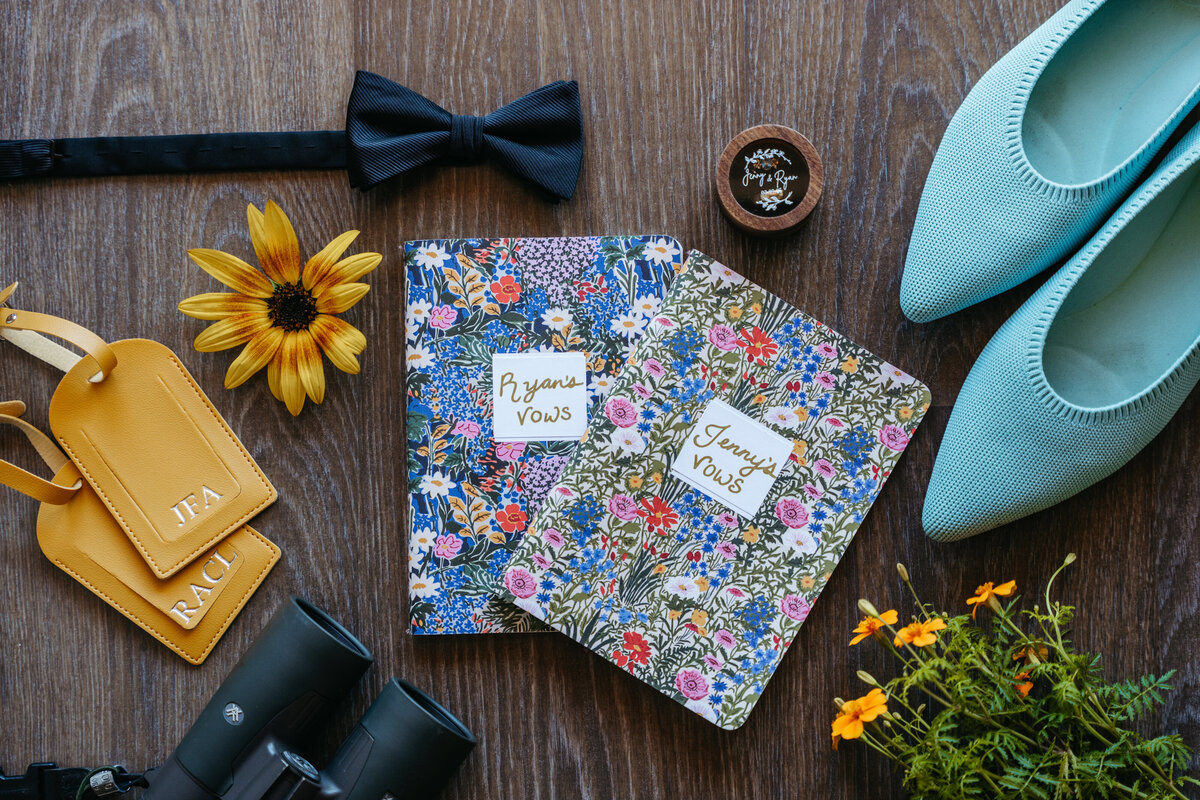 Flatlay of groom’s details with floral bow tie and stationery