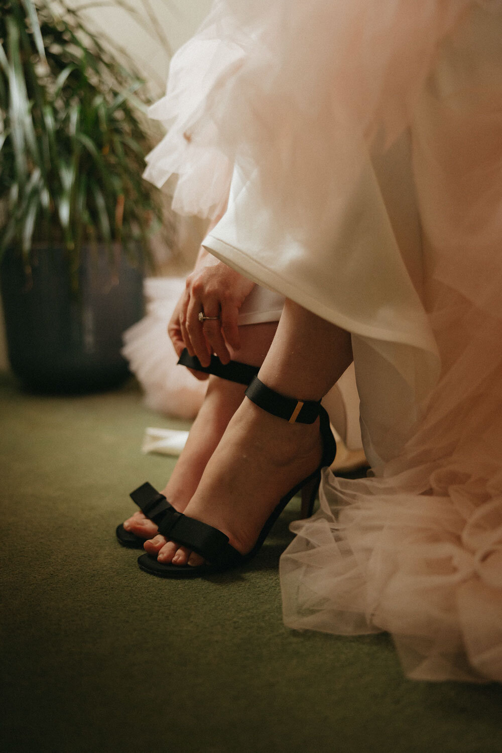 Close-up of bride’s feet in black heels, adjusting her dress