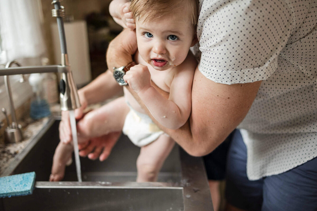 Baby getting sink bath after smash cash first birthday milestone session at home in Cleveland.