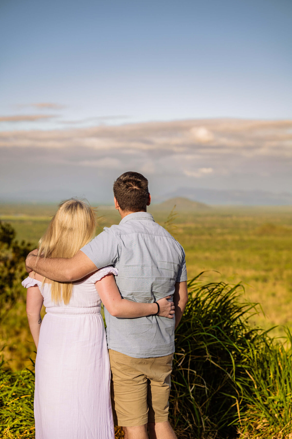 A couple enjoying a scenic view on a hillside in Townsville, Queensland, surrounded by lush greenery and open skies. - photo by Jamie SImmons