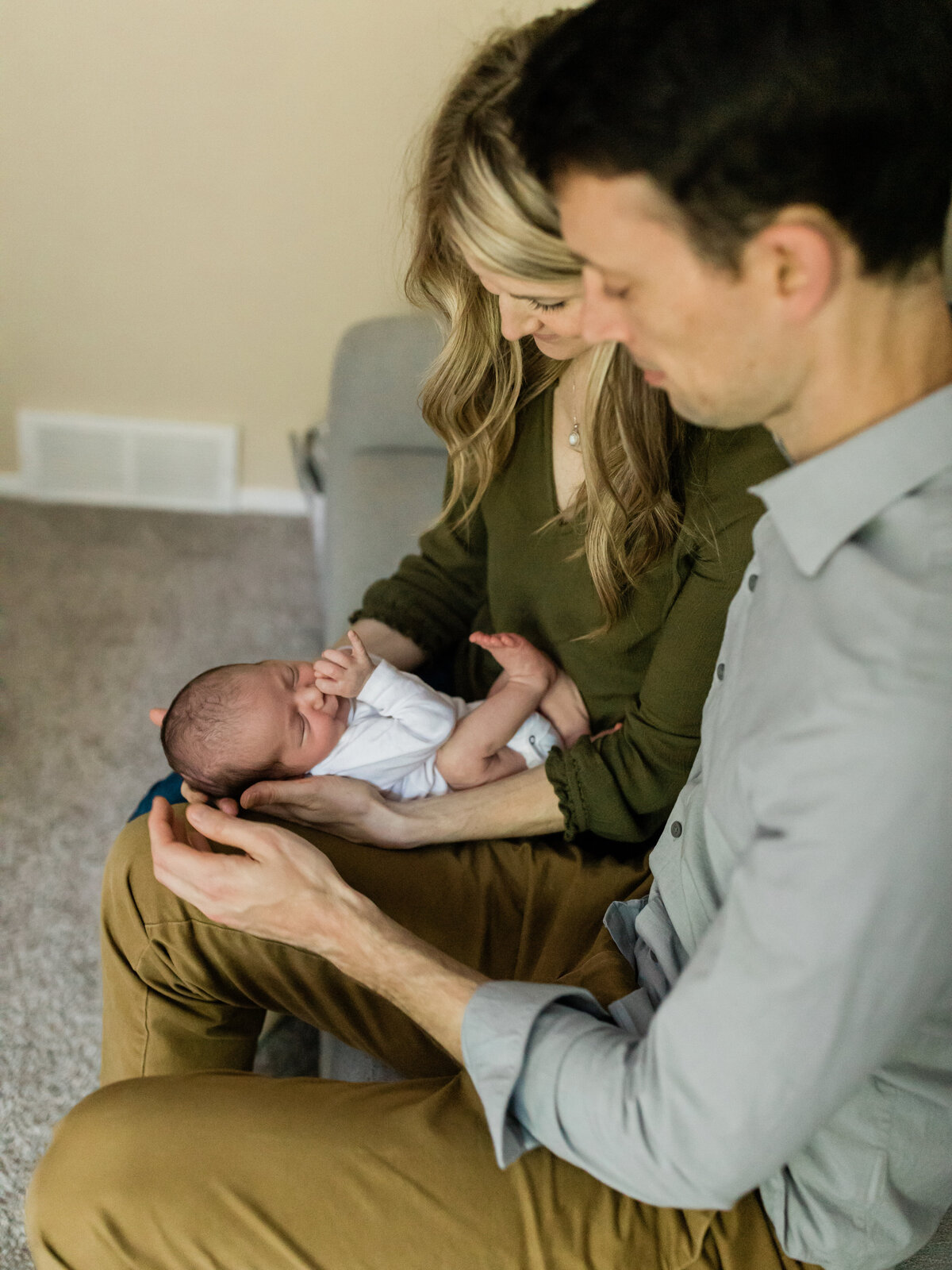 newborn baby boy laying in moms lap next to dad