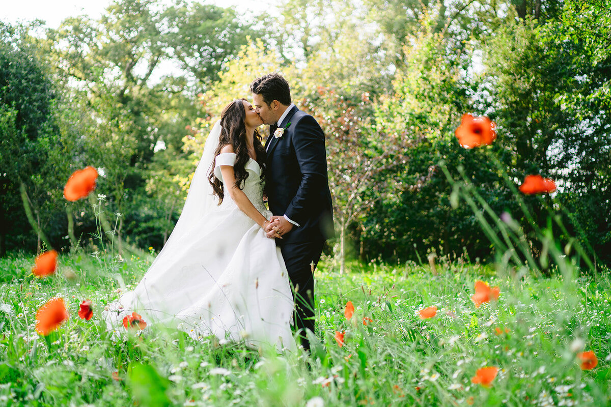 Wedding Planner is giving her groom a kiss after the wedding ceremony in the gardens of Iscoyd Park with the poppies in the foreground