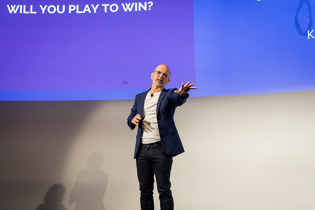 Professional headshot style of business speaker gesturing during motivational keynote on stage new york city.