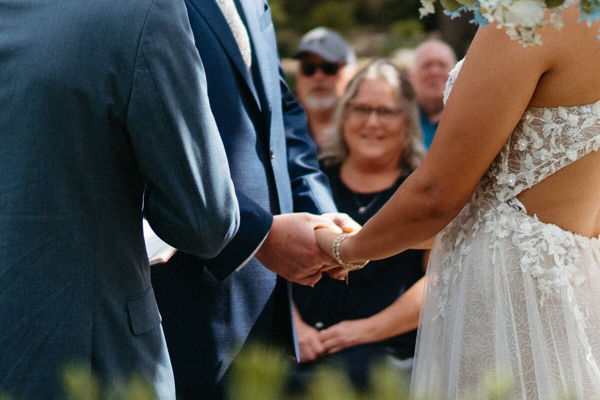 A close up of two people holding hands during their wedding ceremony 