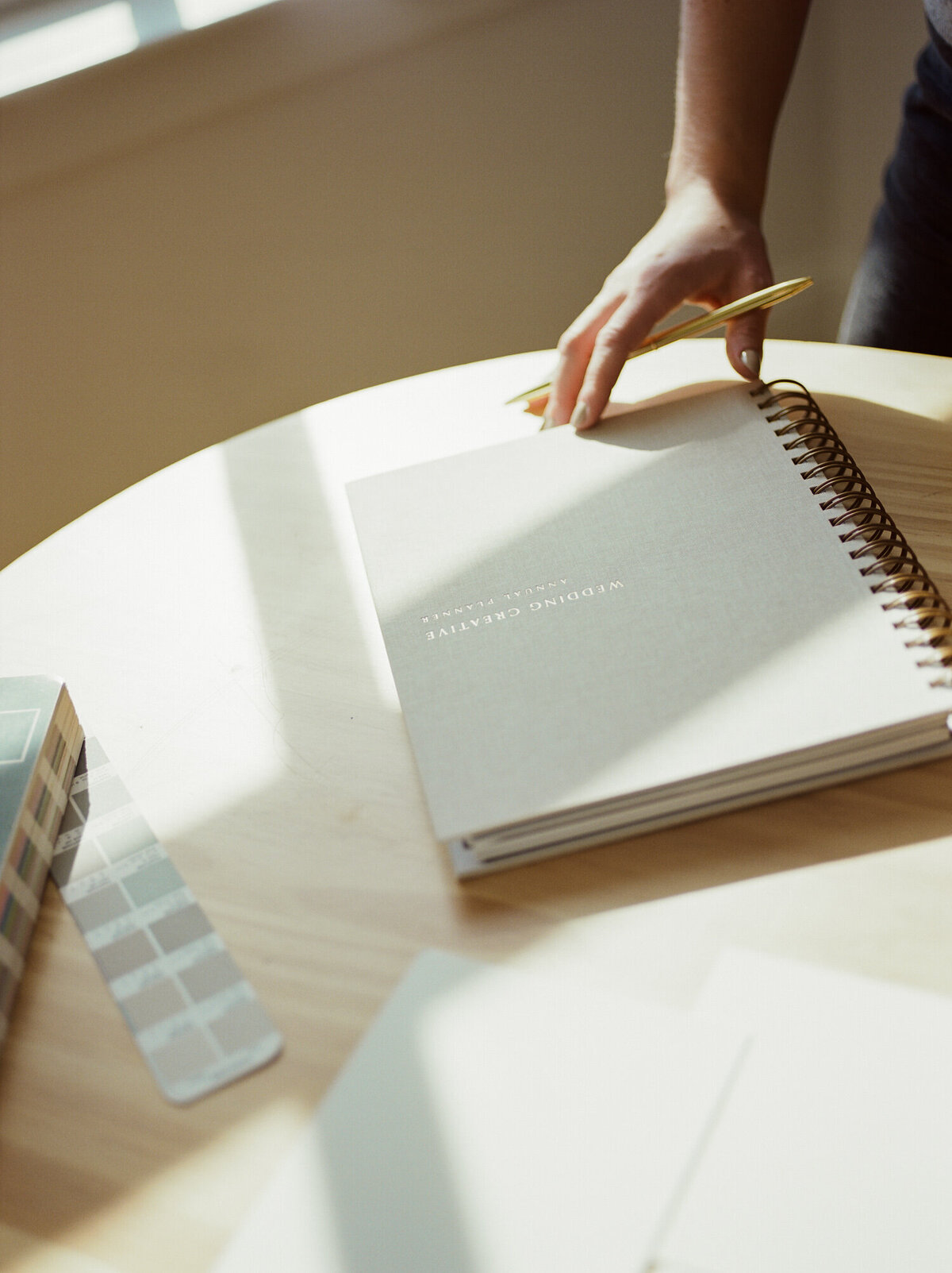 golden natural light, directional light film photography of beige linen planner, gold lettering, hand modeling