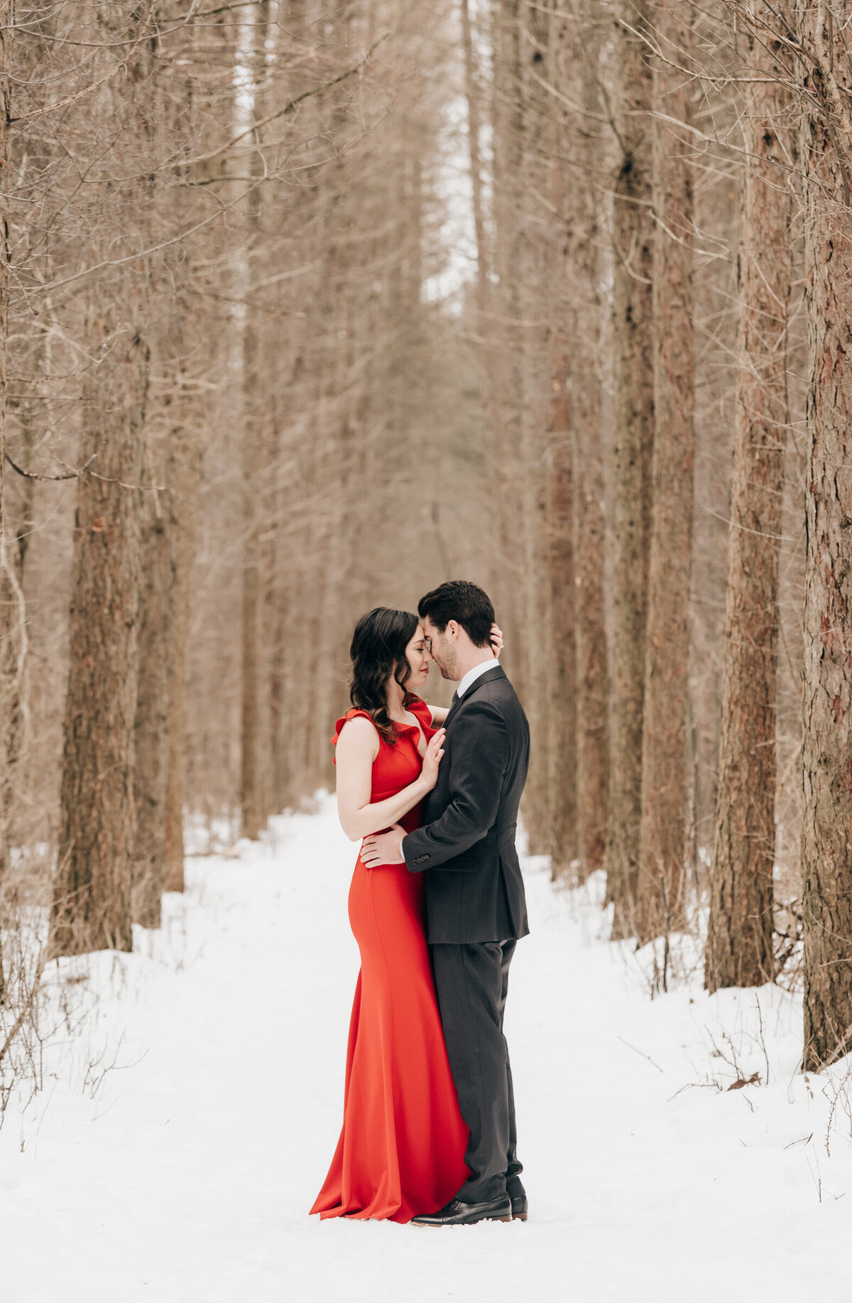 Couple posing in a forest for their Winter engagement session at Fanshawe Conservation Area in London Ontario