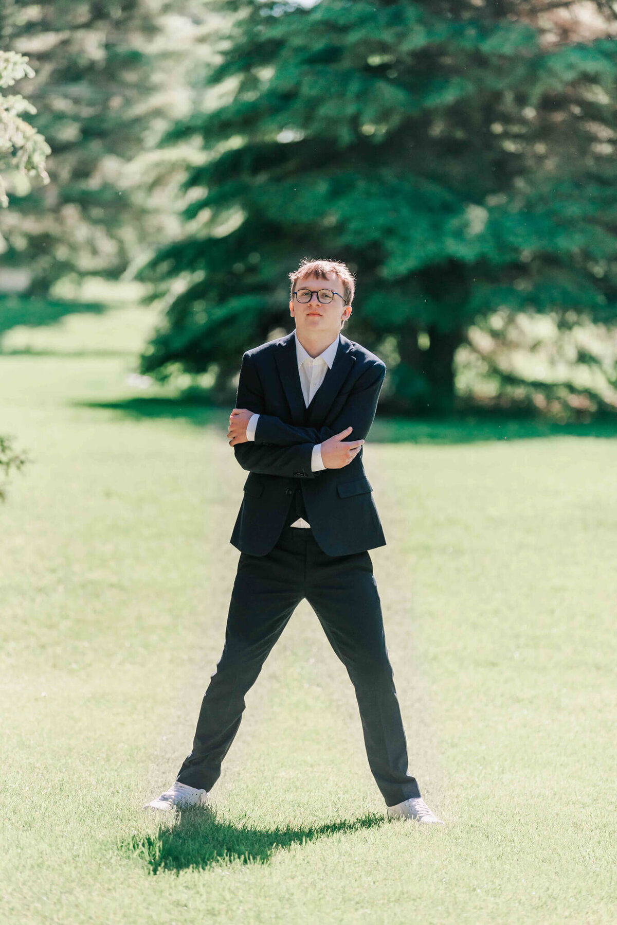 Standing with his arms crossed in the park. 