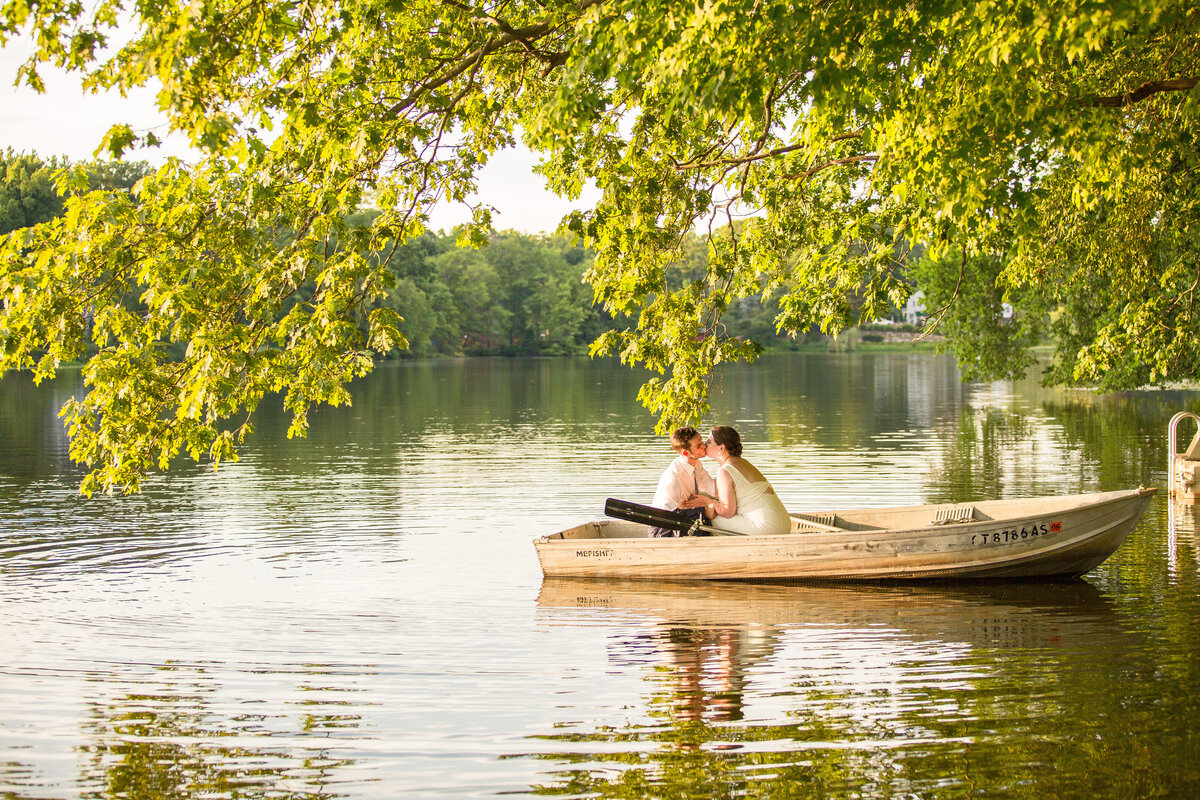 Newlyweds kiss in a rowboat during golden hour.