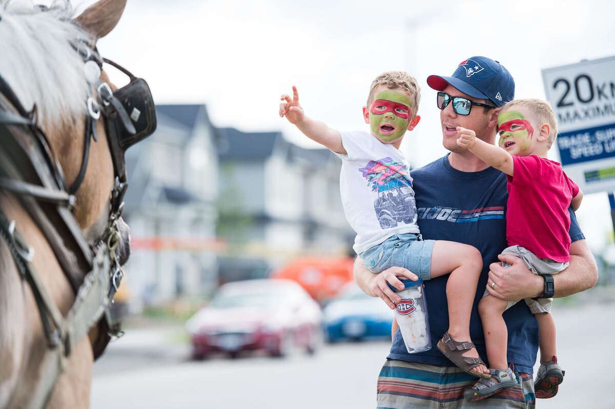 a little boy with face paint getting excited while he pats a horse during a corporate children's event.  Captured by Ottawa Event Photographer JEMMAN Photography COMMERCIAL