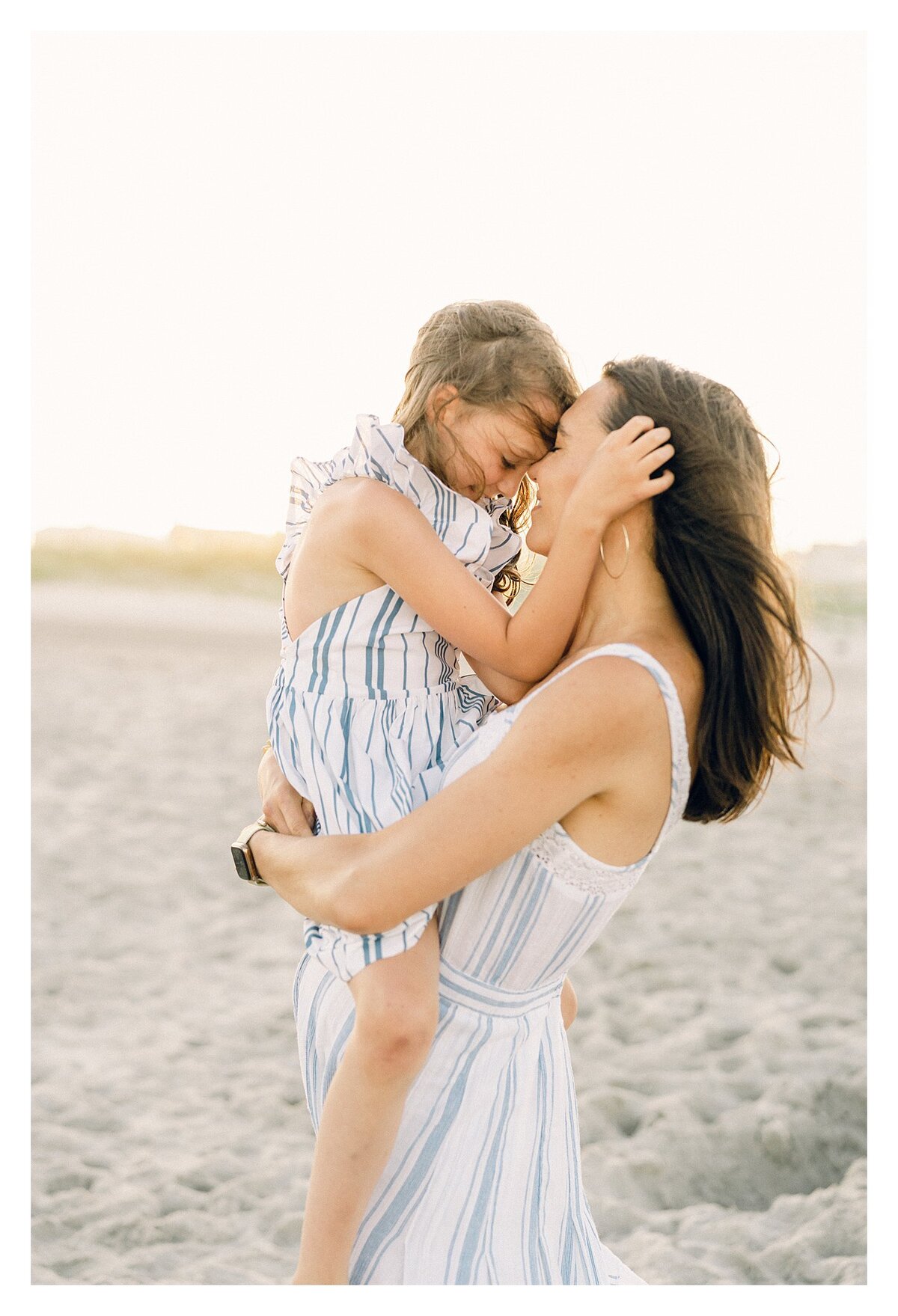 mother and daughter embrace on the beach at sunset