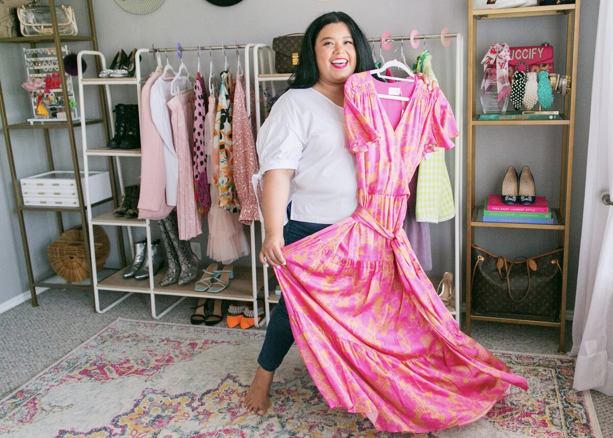 plus size woman holding a dress in closet