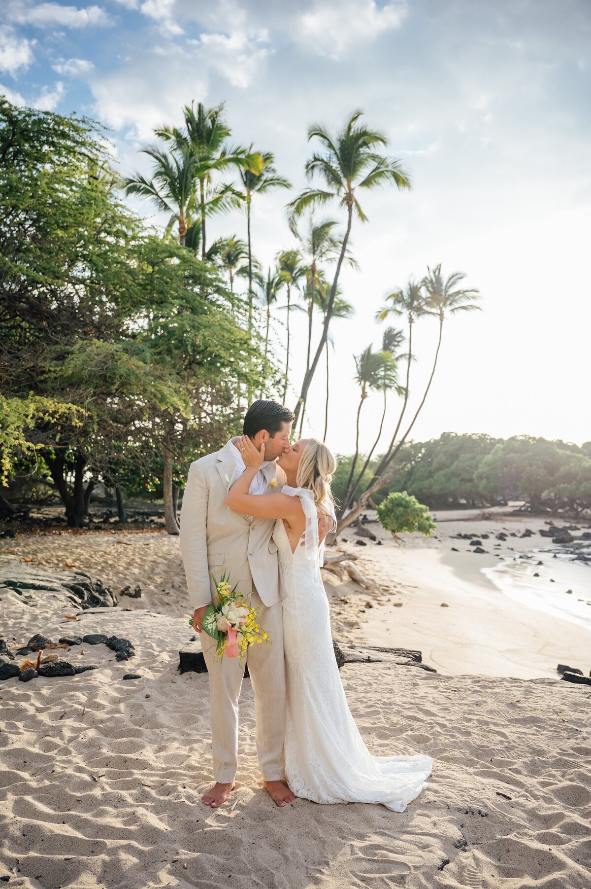a newlywed kiss with palm trees in the backdrop