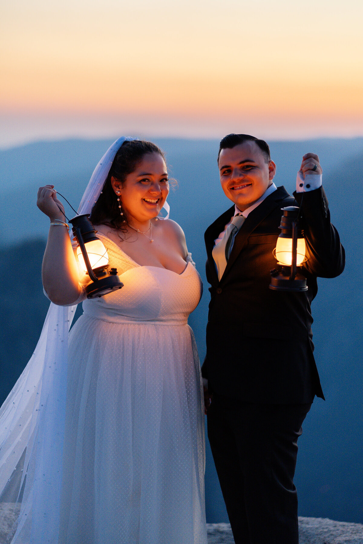 Bride and Groom eloping at Yosemite National Park Taft Point cliff during sunset holding lanterns.