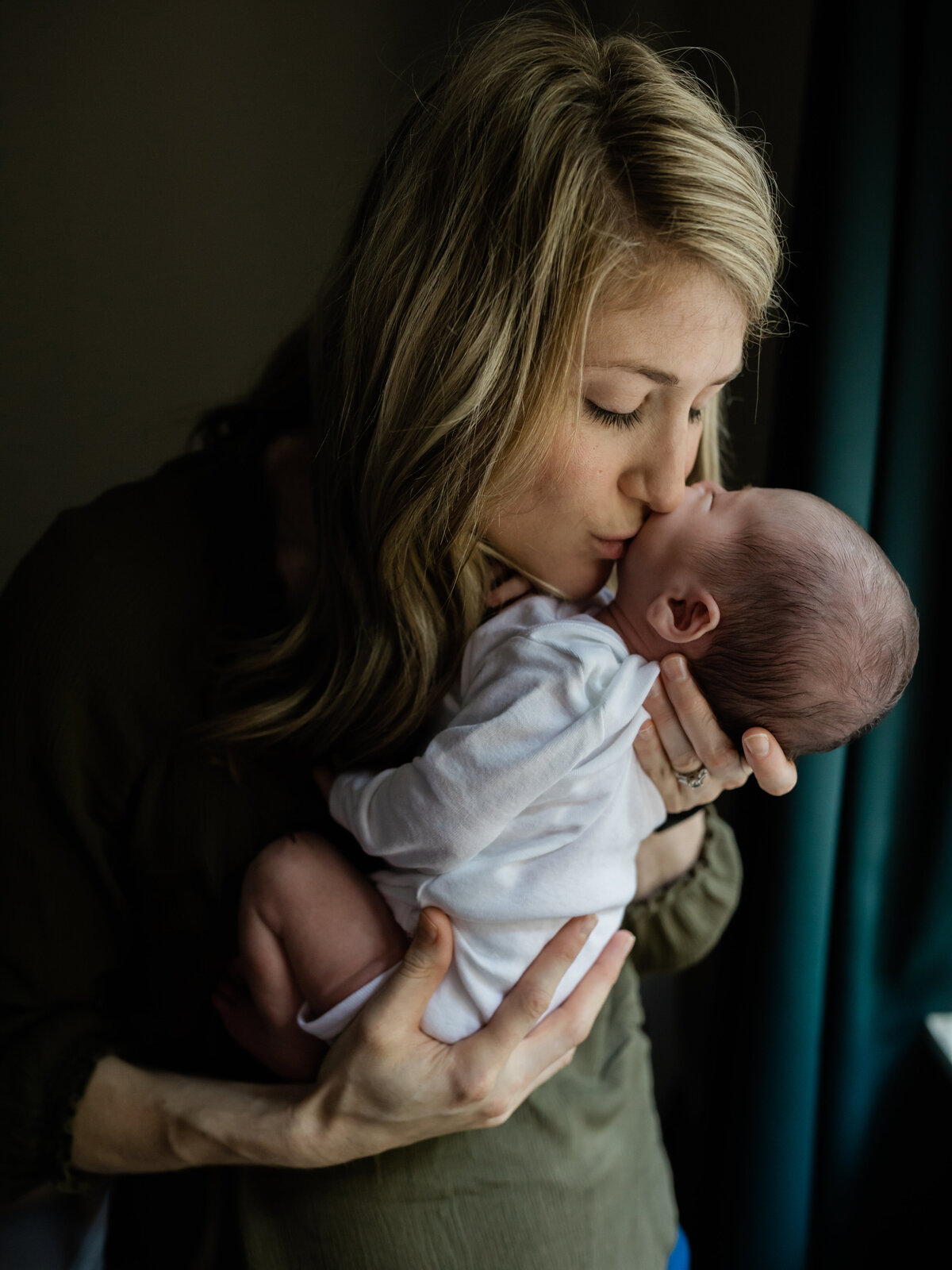 mom kissing newborn baby boy in white onesie cleveland newborn photographer
