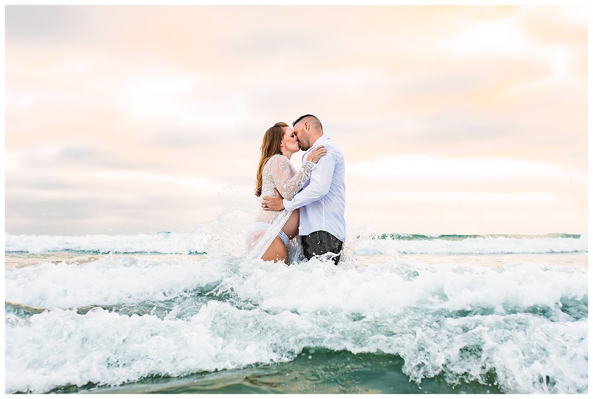 Maternity portrait of couple splashing in the waves in San Diego