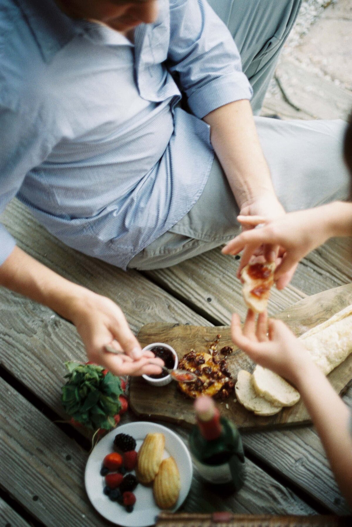 Couple eating bread other pastries on wooden deck.