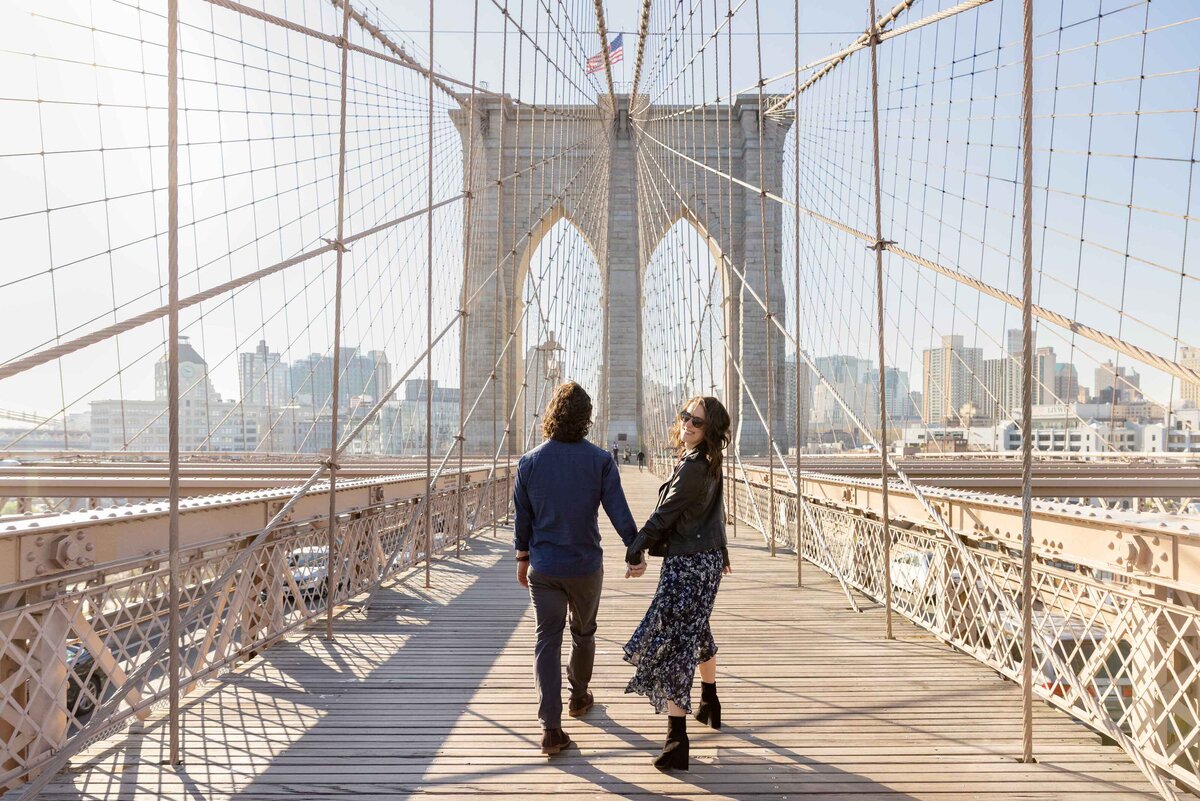 A couple walking along a large bridge together.
