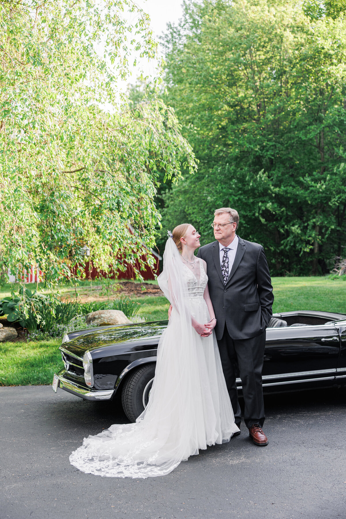 Bride and her father posing in front of a vintage car during her Boylston, MA wedding