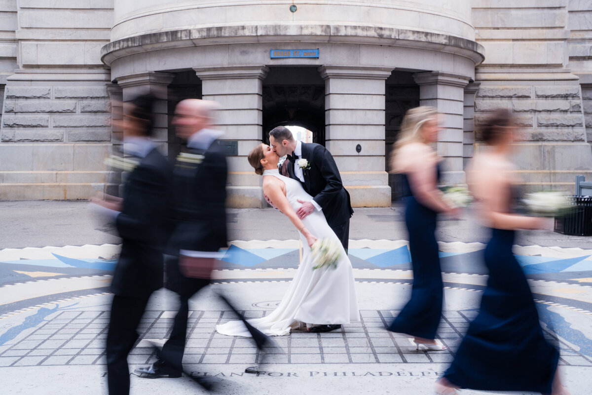 Bridal Party walking by Bride and Groom at The city hall of philadelphia 