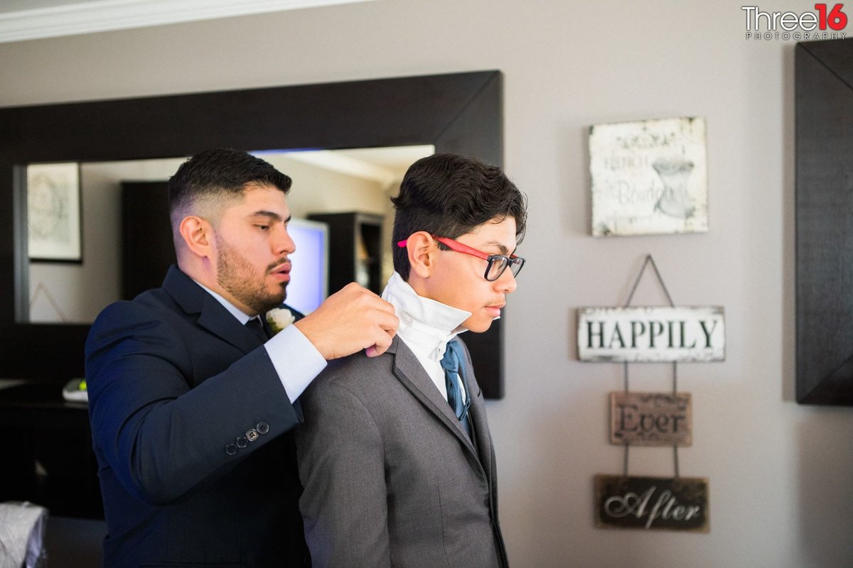 Groom helps Groomsman with his jacket and collar