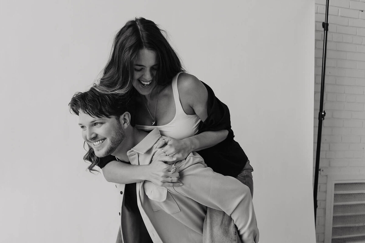 Minnesota wedding photographer rides piggyback on her husband's back.