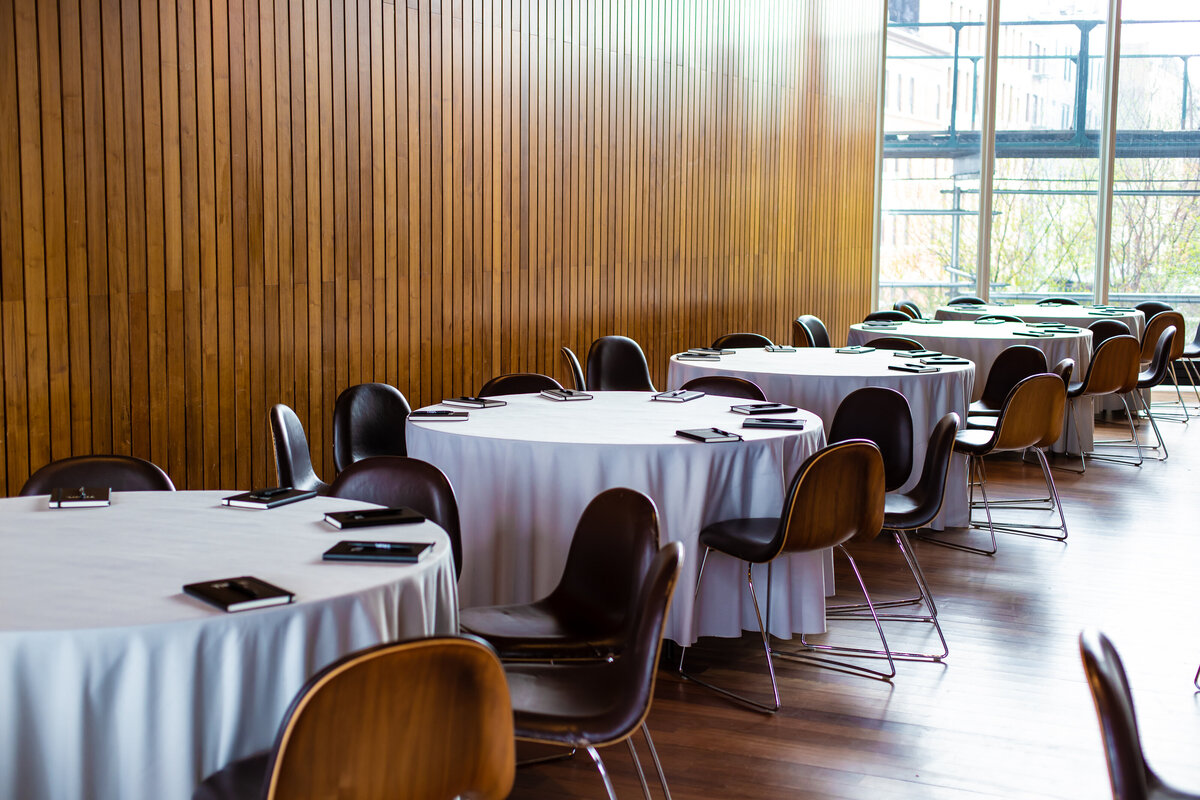 Minimalist dining tables with white linens arranged for Titan Day 2.