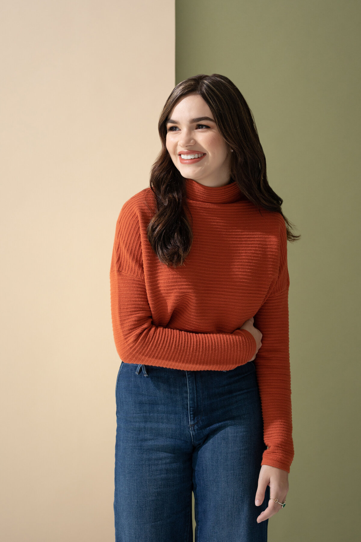 A girl smiling with one arm across her waist