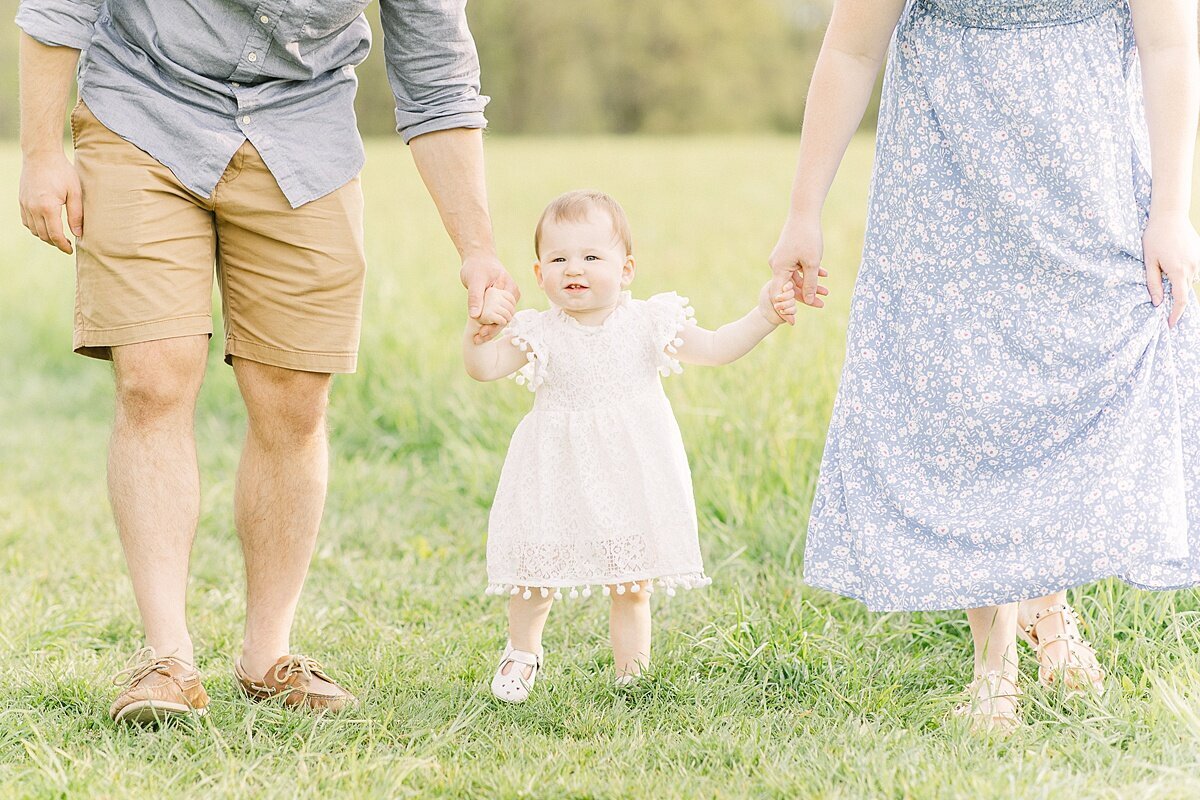 parents hold girls hand duirng spring family photo session with Sara Sniderman Photography in Natick Massachusetts