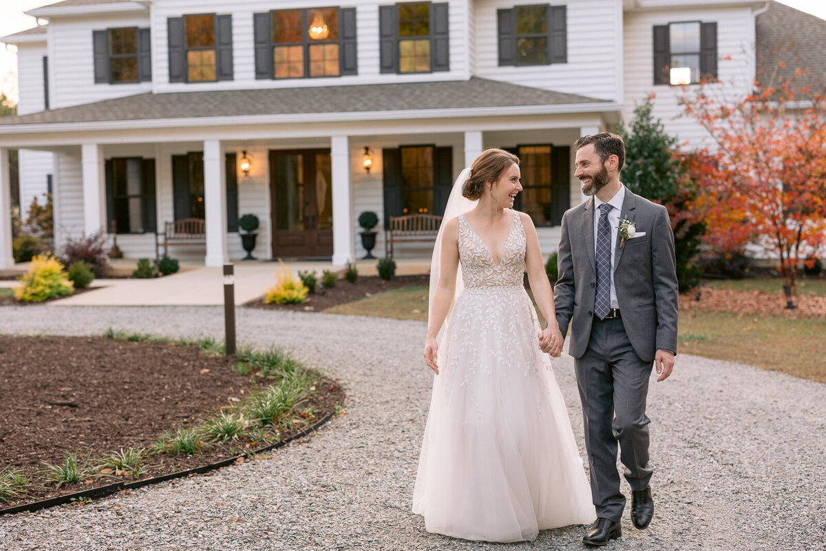 Wedding Photographer, a bride and groom hold hands walking away from a large estate