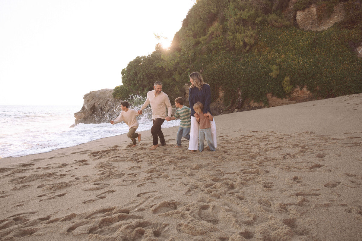 Father and sons walking barefoot on the beach during golden hour at Laguna Beach, CA family photo session